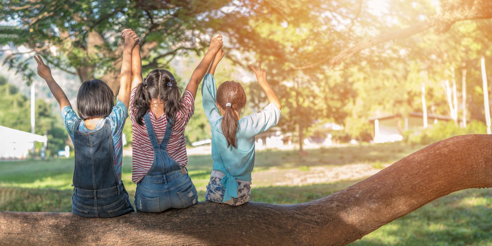 Children friendship concept with happy girl kids in the park having fun sitting under tree shade playing together enjoying good memory and moment of student lifestyle with friends in school time day