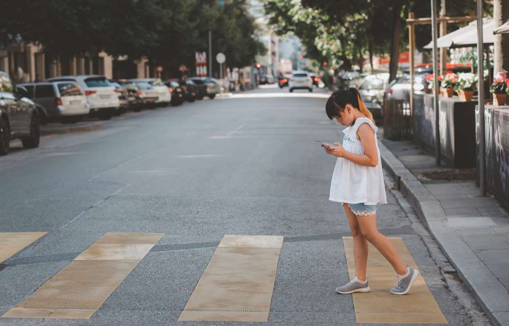 kid on a crosswalk with a phone